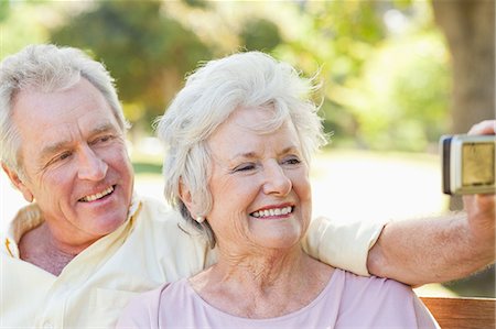 schuldverschreibung - Mann und Frau glücklich lächelnd, als sie posieren für ein Foto auf einer Bank im Park Stockbilder - Premium RF Lizenzfrei, Bildnummer: 6109-06004647