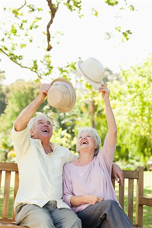 Homme et une femme soulevant leurs chapeaux en étant assis sur un banc dans le parc Photographie de stock - Premium Libres de Droits, Code: 6109-06004644