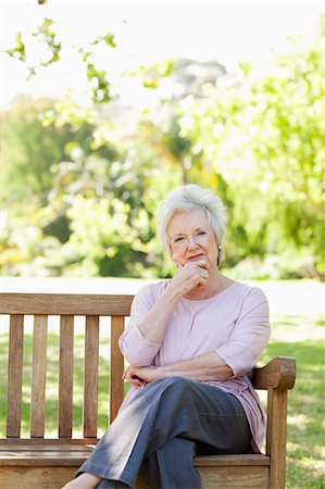 Woman looking ahead thoughtfully as she rests her head on her hand while sitting on a bench in the park Stock Photo - Premium Royalty-Free, Code: 6109-06004658