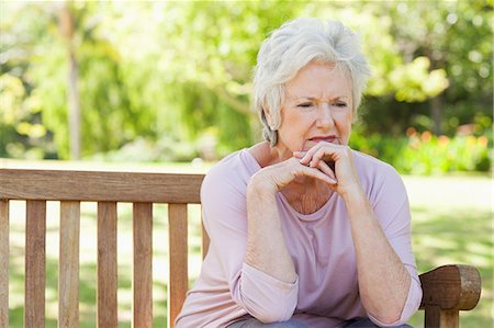 sad - Woman sitting on a bench in the park with a serious expression on her face Stock Photo - Premium Royalty-Free, Code: 6109-06004662