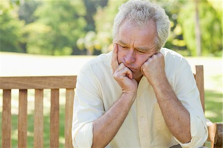 frustration - Man resting his face between his hands as he sits on a bench in a park Stock Photo - Premium Royalty-Free, Code: 6109-06004745