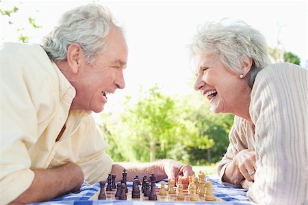 Man and a woman laughing while playing chess in the park Stock Photo - Premium Royalty-Free, Code: 6109-06004787