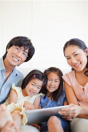 simsearch:6109-06004883,k - A close up shot of the family using the tablet while looking ahead and smiling Foto de stock - Sin royalties Premium, Código: 6109-06004869