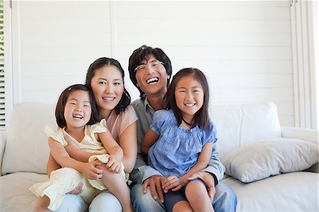 simsearch:6109-06004883,k - The family sitting together and smiling on the couch Foto de stock - Sin royalties Premium, Código: 6109-06004878