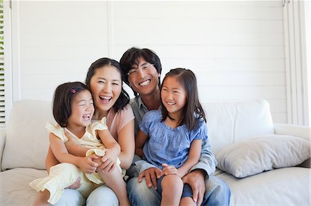 simsearch:6109-06004883,k - The family sitting on the couch and smiling as the mother laughs Foto de stock - Sin royalties Premium, Código: 6109-06004879