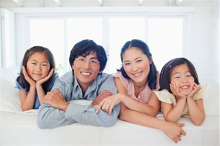 simsearch:6109-06004883,k - The family smiling as they kneel on the couch together Foto de stock - Sin royalties Premium, Código: 6109-06004881