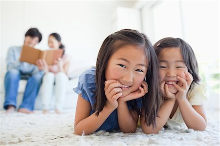 The girls smile and lie on the floor while the parents read a book Foto de stock - Sin royalties Premium, Código: 6109-06004889