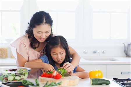 Une mère et fille couper soigneusement les poivrons avec un couteau dans la cuisine. Photographie de stock - Premium Libres de Droits, Code: 6109-06004949