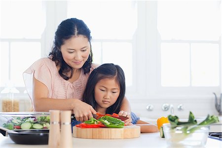 fun dinner - A mother in the kitchen cuts the peppers with a sharp knife as the daughter watches and learns Foto de stock - Sin royalties Premium, Código: 6109-06004951