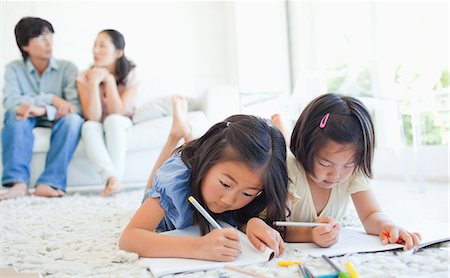 family child drawing - The parents chat on the couch as the girls lie on the ground and colour in their colouring books Stock Photo - Premium Royalty-Free, Code: 6109-06004901