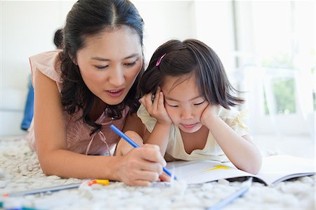 A mother and her daughter are colouring in a book together while lying on the floor Foto de stock - Sin royalties Premium, Código: 6109-06004902