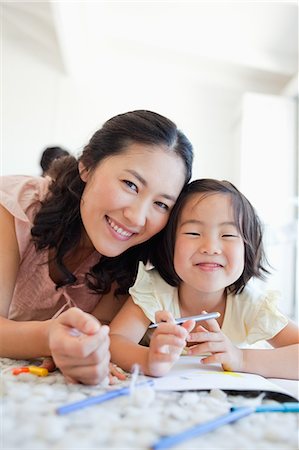 Mother and daughter take a break from colouring and look up to smile Stock Photo - Premium Royalty-Free, Code: 6109-06004906