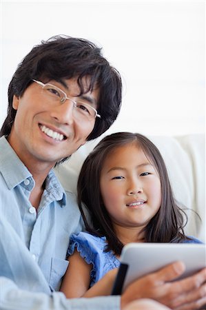 family tablet pc - Un plan d'un père et une fille à l'aide de la tablette pc ensemble sur le canapé rapproché Photographie de stock - Premium Libres de Droits, Code: 6109-06004928