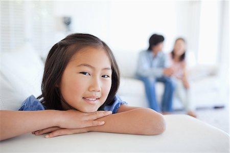 A girl sits at the end of the couch as her parents sit at the back of the couch Stock Photo - Premium Royalty-Free, Code: 6109-06004934