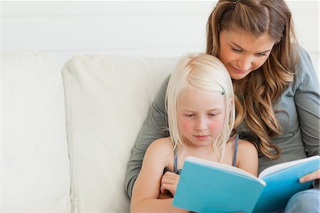 parent reading child - A close up of a girl and her mom reading a book together as they sit on the couch Foto de stock - Sin royalties Premium, Código: 6109-06005045