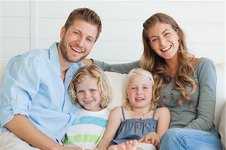 family beautiful - A smiling happy family sit on the couch together as they look straight ahead Stock Photo - Premium Royalty-Free, Code: 6109-06005050