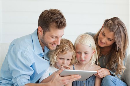 Les enfants sont assis entre leurs parents regarder un tablet pc qui est détenu par leurs parents Photographie de stock - Premium Libres de Droits, Code: 6109-06005051