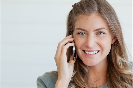 Un plan d'une femme souriante, à l'aide de son téléphone mobile pour bavarder tout en regardant droit devant rapproché Photographie de stock - Premium Libres de Droits, Code: 6109-06005027