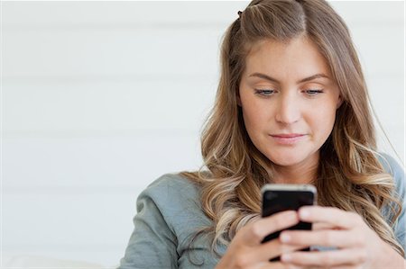 phone young caucasian woman relaxed - A woman sitting on the couch using her phone to send a text message Stock Photo - Premium Royalty-Free, Code: 6109-06005030