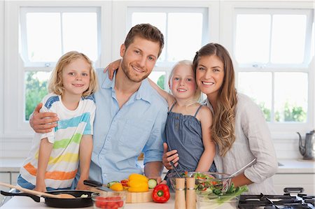 A smiling family all in the kitchen as they begin to prepare dinner Stock Photo - Premium Royalty-Free, Code: 6109-06005142