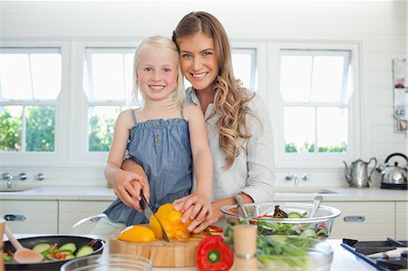 A smiling mother and daughter together in the kitchen cutting peppers Stock Photo - Premium Royalty-Free, Code: 6109-06005151