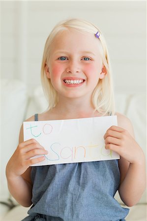 Un enfant heureux sourit comme elle a écrit sa lettre à envoyer au père Noël Photographie de stock - Premium Libres de Droits, Code: 6109-06005117