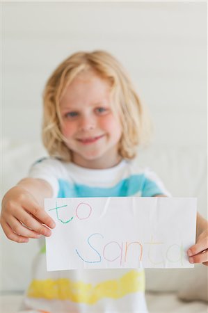 Un petit garçon souriant détient sa lettre au père Noël en face de lui Photographie de stock - Premium Libres de Droits, Code: 6109-06005125