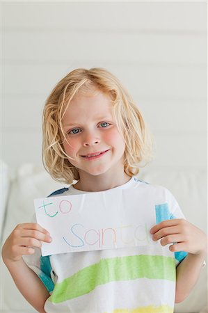 Un jeune garçon souriant détient sa lettre au père Noël près de sa poitrine Photographie de stock - Premium Libres de Droits, Code: 6109-06005126