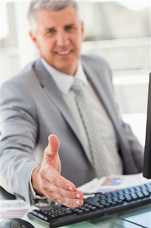 shaking hands desk - Boss holding out his hand in a bright office Stock Photo - Premium Royalty-Free, Code: 6109-06005297