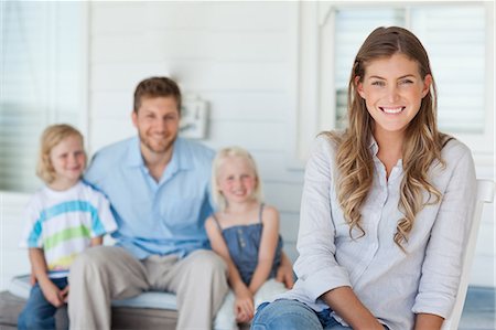 simsearch:6109-06005216,k - An attractive woman sits on her chair as her husband and kids sit behind her Foto de stock - Sin royalties Premium, Código: 6109-06005209