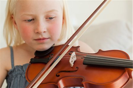 Une fille jouant du violon, alors qu'elle regarde les cordes pour s'assurer qu'elle joue les notes de droits Photographie de stock - Premium Libres de Droits, Code: 6109-06005238