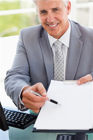simsearch:6109-06005455,k - Portrait of a boss showing a file in a bright office Fotografie stock - Premium Royalty-Free, Codice: 6109-06005344