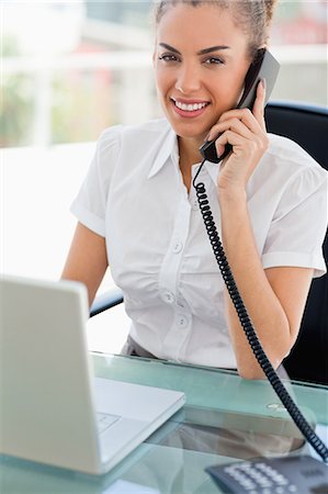 simsearch:6109-06005396,k - Portrait d'une femme aux cheveux crépuse souriant tout en téléphonant à un bureau lumineux Photographie de stock - Premium Libres de Droits, Code: 6109-06005360