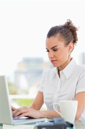 stern woman - Frizzy haired woman tapping on her laptop in a bright office Stock Photo - Premium Royalty-Free, Code: 6109-06005377