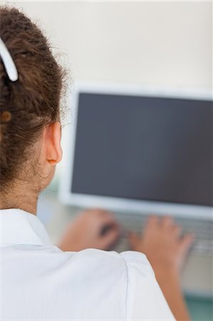 Tanned woman using a laptop with black screen in a bright office Foto de stock - Sin royalties Premium, Código: 6109-06005384