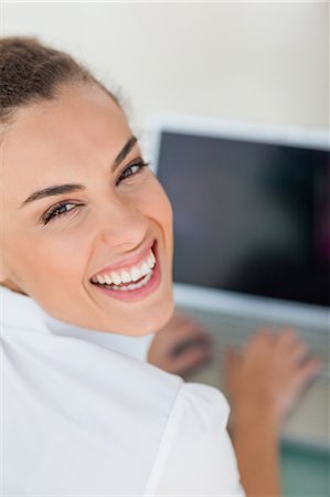 Portrait of a tanned woman using a laptop with black screen in a bright office Stock Photo - Premium Royalty-Free, Code: 6109-06005385