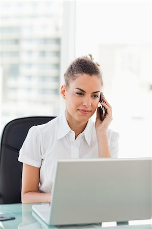 Tanned businesswoman using her cellphone in a bright office Foto de stock - Royalty Free Premium, Número: 6109-06005397