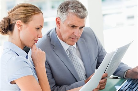 pruebas - Man wearing a suit and a woman intently studying information on business reports while sitting behind a laptop Foto de stock - Sin royalties Premium, Código: 6109-06005318