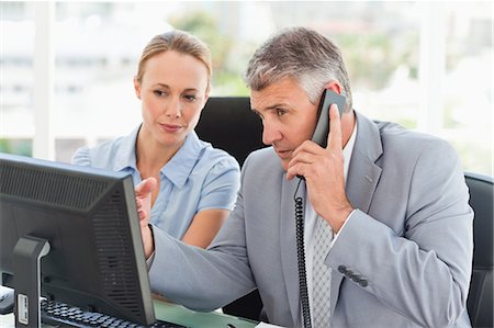 suit female - Boss on the phone while an employee is next to him in a bright office Stock Photo - Premium Royalty-Free, Code: 6109-06005321