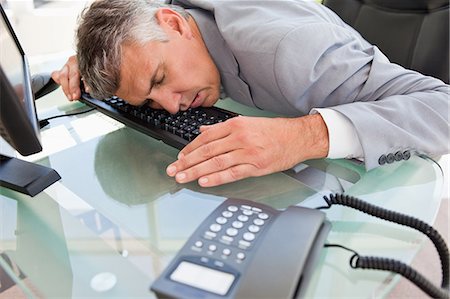 executive sleeping desk - Businessman sleeping on his keyboard in a bright office Stock Photo - Premium Royalty-Free, Code: 6109-06005337