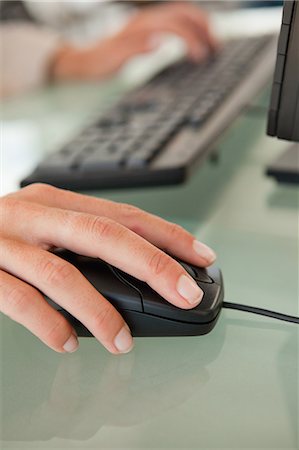 Woman's hand moving a mouse on a glass desk Fotografie stock - Premium Royalty-Free, Codice: 6109-06005459