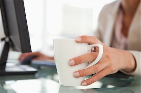 Close-up of a woman hand taking a mug on a glass desk Stock Photo - Premium Royalty-Free, Code: 6109-06005460