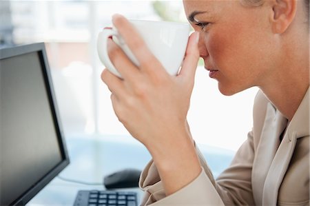 Close-up of a woman holding a mug on a glass desk while looking at her screen Stock Photo - Premium Royalty-Free, Code: 6109-06005461