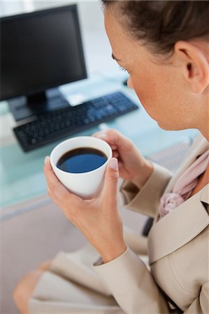 simsearch:6109-06005486,k - Gros plan d'une femme d'affaires détenant un café devant son ordinateur Photographie de stock - Premium Libres de Droits, Code: 6109-06005469