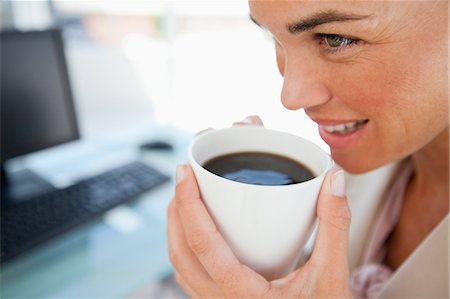 Close-up of a businesswoman with a coffee in front of her computer Stock Photo - Premium Royalty-Free, Code: 6109-06005471