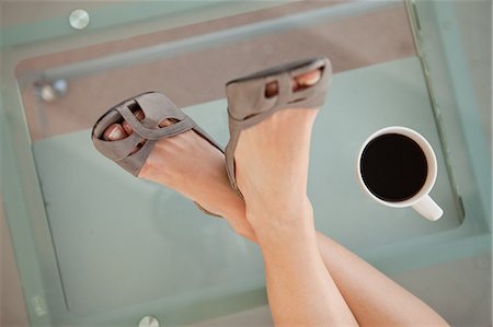 footwear - High angle-shot on businesswoman's feet on a glass desk next to a coffee cup Stock Photo - Premium Royalty-Free, Code: 6109-06005475