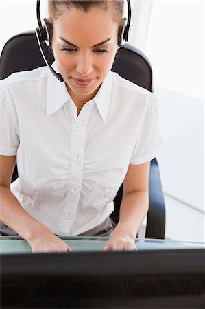 Tanned businesswoman using a computer with headset in bright office Stock Photo - Premium Royalty-Free, Code: 6109-06005424
