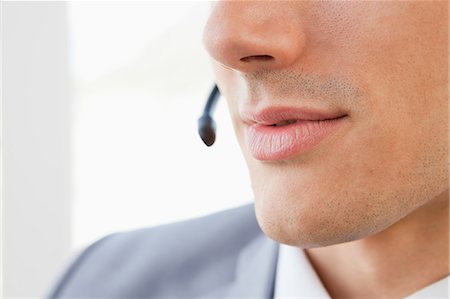 Gros plan de la bouche d'un homme parler avec un casque d'écoute dans un bureau lumineux Photographie de stock - Premium Libres de Droits, Code: 6109-06005545