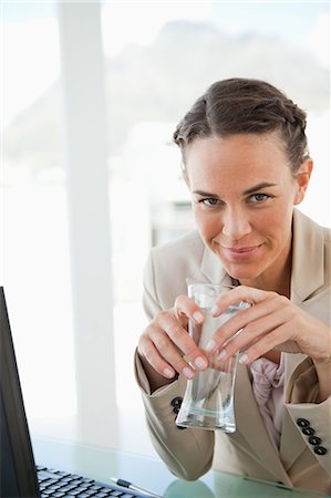 simsearch:6109-06005396,k - Portrait d'une femme tenant un verre d'eau dans un bureau lumineux Photographie de stock - Premium Libres de Droits, Code: 6109-06005502