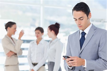 female cross arms confident smile - Young businessman typing text message with colleagues behind him Stock Photo - Premium Royalty-Free, Code: 6109-06005661